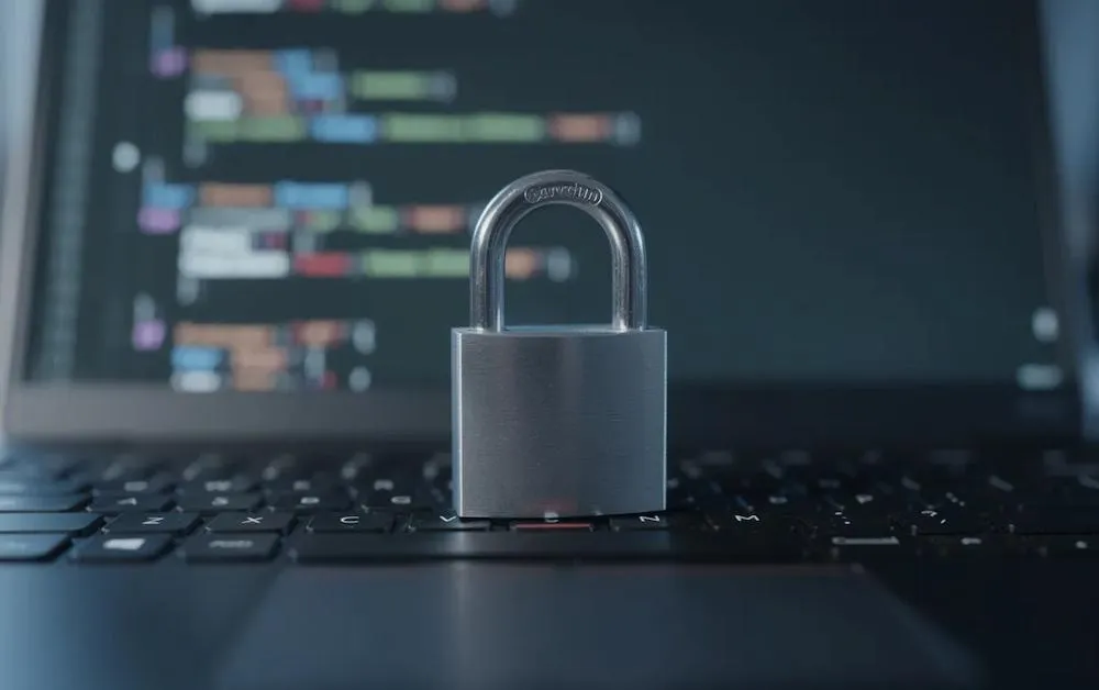 Padlock resting on a laptop keyboard in front of code