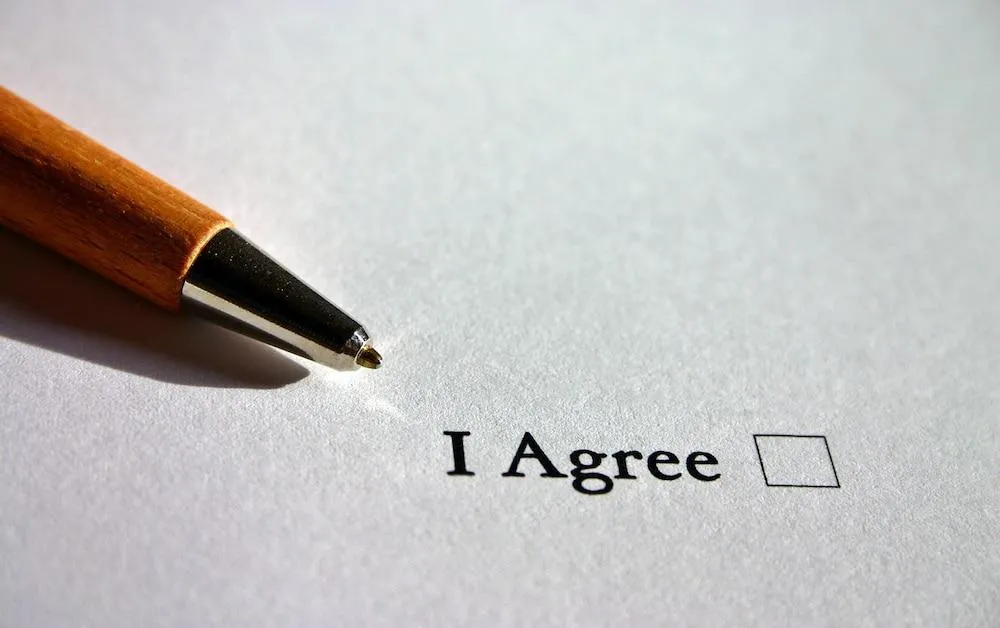 Pen beside an empty I Agree checkbox on paper